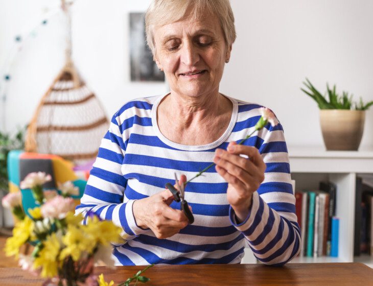 Older woman puts together a beautiful yellow flower arrangement for her living space