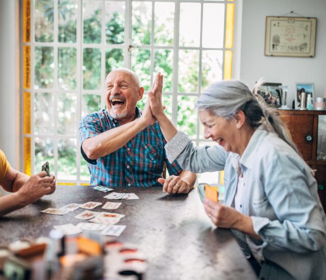 group of seniors enthusiastically enjoying a card game together